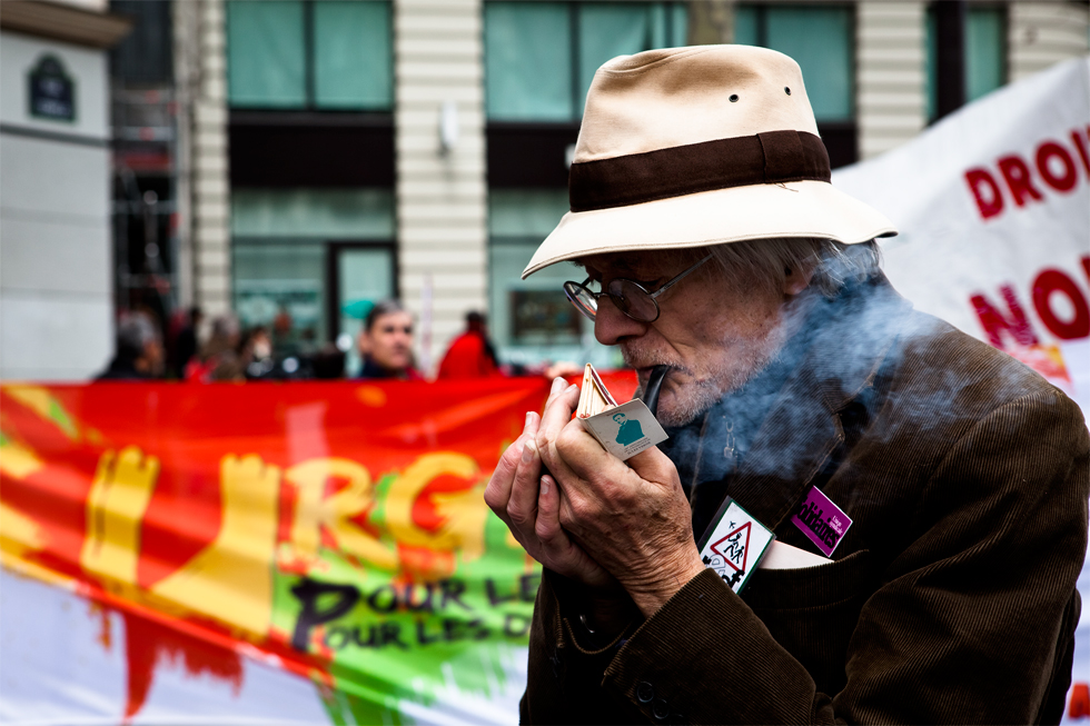 homme allumant sa pipe pendant manifestation a Paris