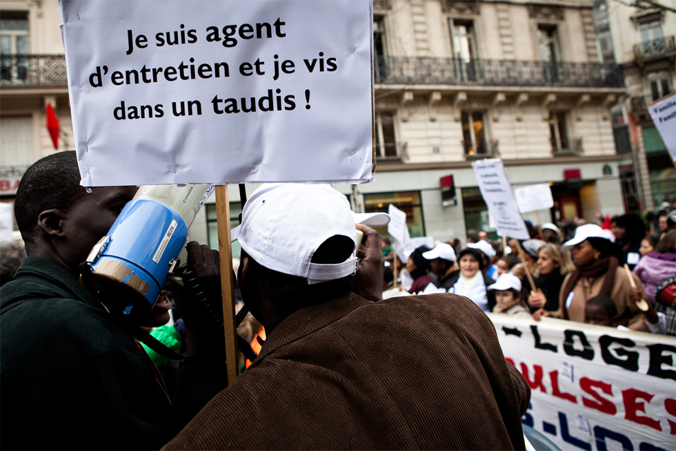 hommes avec megaphone et banderole pendant manifestation
